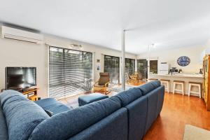 a living room with a blue couch and a kitchen at The Treehouse at Long Beach in Long Beach