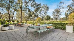 a patio with a table and benches and trees at Hunter Grange - The Vintage in Pokolbin