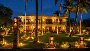 a resort with palm trees and lights at night at CPS Lihini Beach Hotel in Induruwa