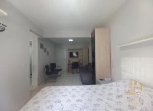 a bedroom with a bed and a room with chairs at Loft Ponta Aguda in Blumenau