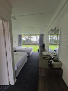 a hotel room with two beds and a mirror at Hilltop Hotel in Goonellabah