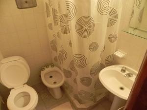 Un baño con inodoro y cortina de ducha. en Hotel Tritones, en Pinamar