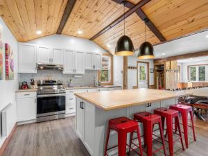 a kitchen with white cabinets and red bar stools at Rustic & Charming Mont Blanc Chalet Private Spa in Saint-Faustin