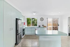 a white kitchen with a refrigerator and a sink at Light and Bright at Maloneys in Maloney's Beach