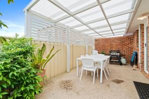a patio with a white table and chairs at Light and Bright at Maloneys in Maloney's Beach