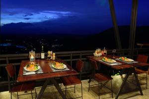 dos mesas con platos de comida en un balcón por la noche en At Tree Resort Khaokho, en Khao Kho