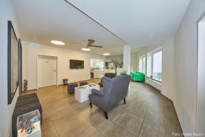 a living room with a couch and chairs and a tv at Waldhotel Brand's Busch in Bielefeld