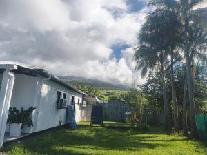 a white house with palm trees in a yard at Gite, Route Des Laves in Saint-Philippe