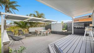 a patio with a table and chairs on a deck at 19 Newry St in Nambucca Heads