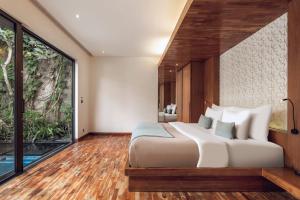 a bedroom with a large bed and a large window at Ayona Villa Seminyak by Ini Vie Hospitality in Seminyak