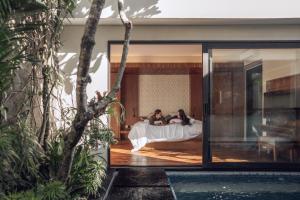 a man and a woman laying in bed in a house at Ayona Villa Seminyak by Ini Vie Hospitality in Seminyak