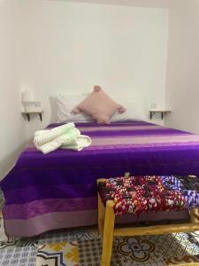 a bed with a purple comforter in a room at Riad hotel borj in Tétouan