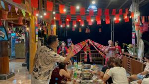a woman holding an umbrella over a table with people at House By The Stream in Lũng Tiềm