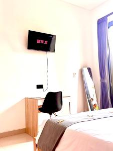 a bedroom with a bed and a desk with a monitor on the wall at D'rei guesthouse in Canggu