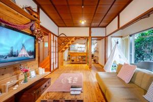a living room with a couch and a large screen tv at The Sticks Inatori in Higashiizu