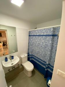 a bathroom with a toilet and a sink and a shower curtain at Casa Laguna Suites in Concepción