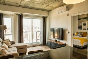 a living room with a bed a couch and a tv at Caïman - Le1006 in Quebec City