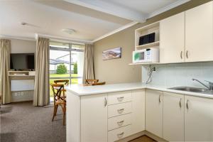 a kitchen with white cabinets and a sink at Methven Nest Apartment in Methven