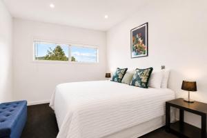 a bedroom with a white bed and a blue chair at Alpine Vista with Mountain Views, Pool and Spa in Wanaka +17 photos