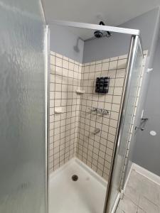 a shower with a glass door in a bathroom at Grey comfort room in New London