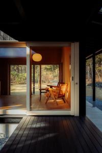 a glass door of a house with a table and a bench at SHISHI-IWA HOUSE Karuizawa in Karuizawa