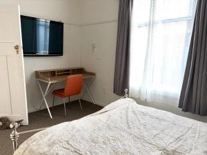 a bedroom with a desk and a tv and a bed at Pretty Villa Close to St Clair Beach private parking in Dunedin