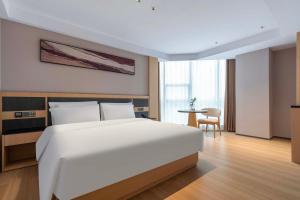 a bedroom with a large white bed and a table at YIBON INTERNATIONAL HOTEL in Guiyang