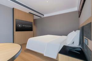 a bedroom with a white bed and a table at YIBON INTERNATIONAL HOTEL in Guiyang