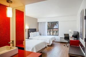 a hotel room with two beds and a television at Fiesta Inn Saltillo in Saltillo