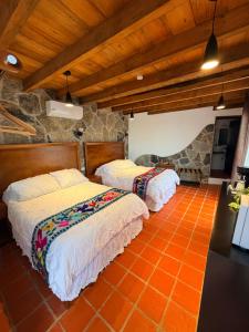 two beds in a room with an orange tile floor at La Peña Hotel Boutique & SPA in Cuetzalán del Progreso +89 photos
