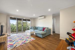 a living room with a couch and a tv at Sandy Toes Retreat in Smiths Beach