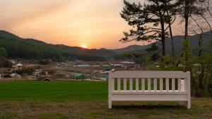 a white bench sitting in a field at sunset at Taean Atirans Beach Pension in Taean