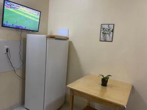 a refrigerator in a room with a table and a tv at Apartamento Colinas in Cacoal