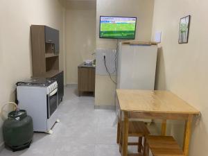 a kitchen with a refrigerator and a table and a television at Apartamento Colinas in Cacoal