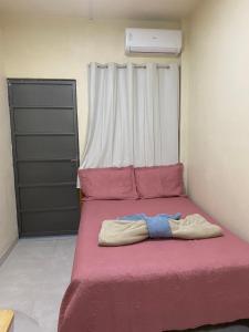 a bed in a room with a pink blanket at Apartamento Colinas in Cacoal