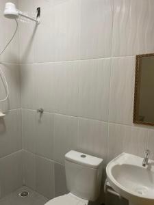a white bathroom with a toilet and a sink at Apartamento Colinas in Cacoal +16 photos