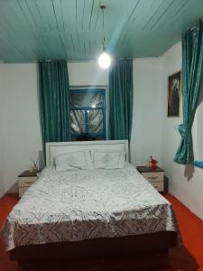 a bedroom with a bed with a blue ceiling and green curtains at Madriel Eko Retreat in Bokonbayevo