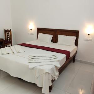 a bedroom with a large bed with white sheets at Hotel Neptune Kovalam in Trivandrum