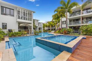 a swimming pool in front of a building at Sand Dunes Resort Accommodation in Marcoola