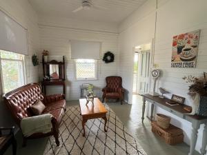 a living room with leather chairs and a table at Oakmore Cottage Charming Old Vintage Queenslander - Central location in Bundaberg