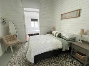 a bedroom with a bed and a chair and a window at Oakmore Cottage Charming Old Vintage Queenslander - Central location in Bundaberg