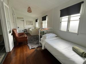 a bedroom with two beds and a chair at Oakmore Cottage Charming Old Vintage Queenslander - Central location in Bundaberg