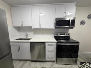 a kitchen with white cabinets and a stove and a microwave at Havilah Cozy in Regina