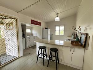 a kitchen with two bar stools and a counter top at Oakmore Cottage Charming Old Vintage Queenslander - Central location in Bundaberg +12 photos