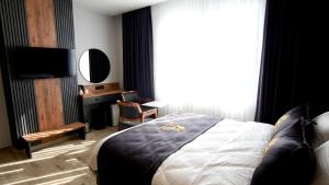 a bedroom with a bed and a desk and a television at Aerohub Grand Hotel in Arnavutköy
