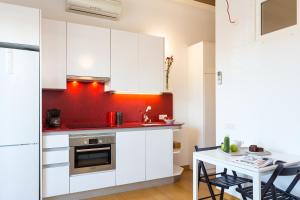 バルセロナにあるCasa Cosi Sant Antoniの白いキャビネットと赤い壁のキッチン