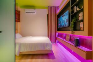 a bedroom with a bed and a tv and purple lighting at Benri Hotel Signature in Ho Chi Minh City