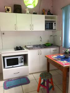 a kitchen with white cabinets and a table with a microwave at Pousada Recanto Gramado in Gramado