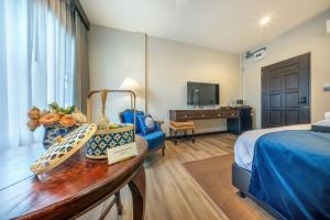 a hotel room with a bedroom with a bed and a table at Apirom Hometel in Sathani Lak Si