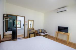 a bedroom with a white bed and a television at First light beach hin kong in Hinkong